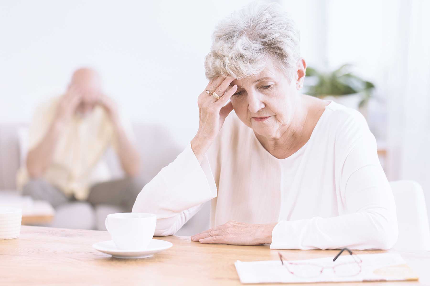 Photo of a sad-looking senior woman sitting at a table.