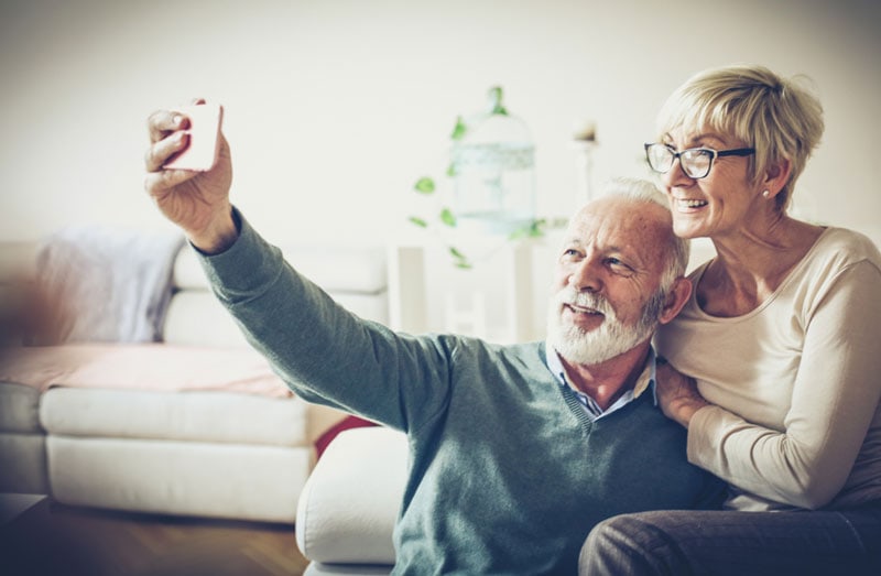 Senior couple taking self portrait together at home.