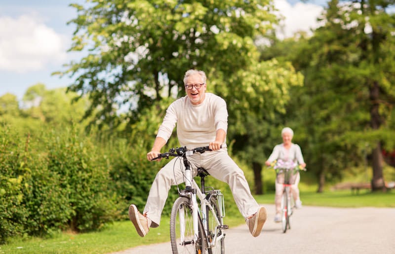 happy senior couple riding bicycles at summer park