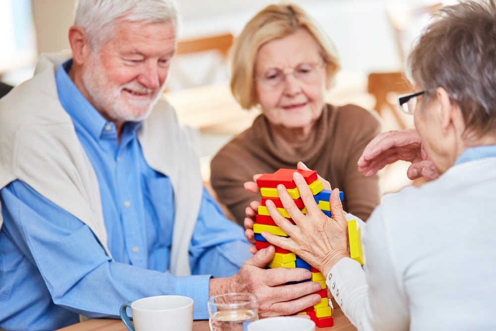 Seniors with dementia play with building blocks and build a tower in the nursing home