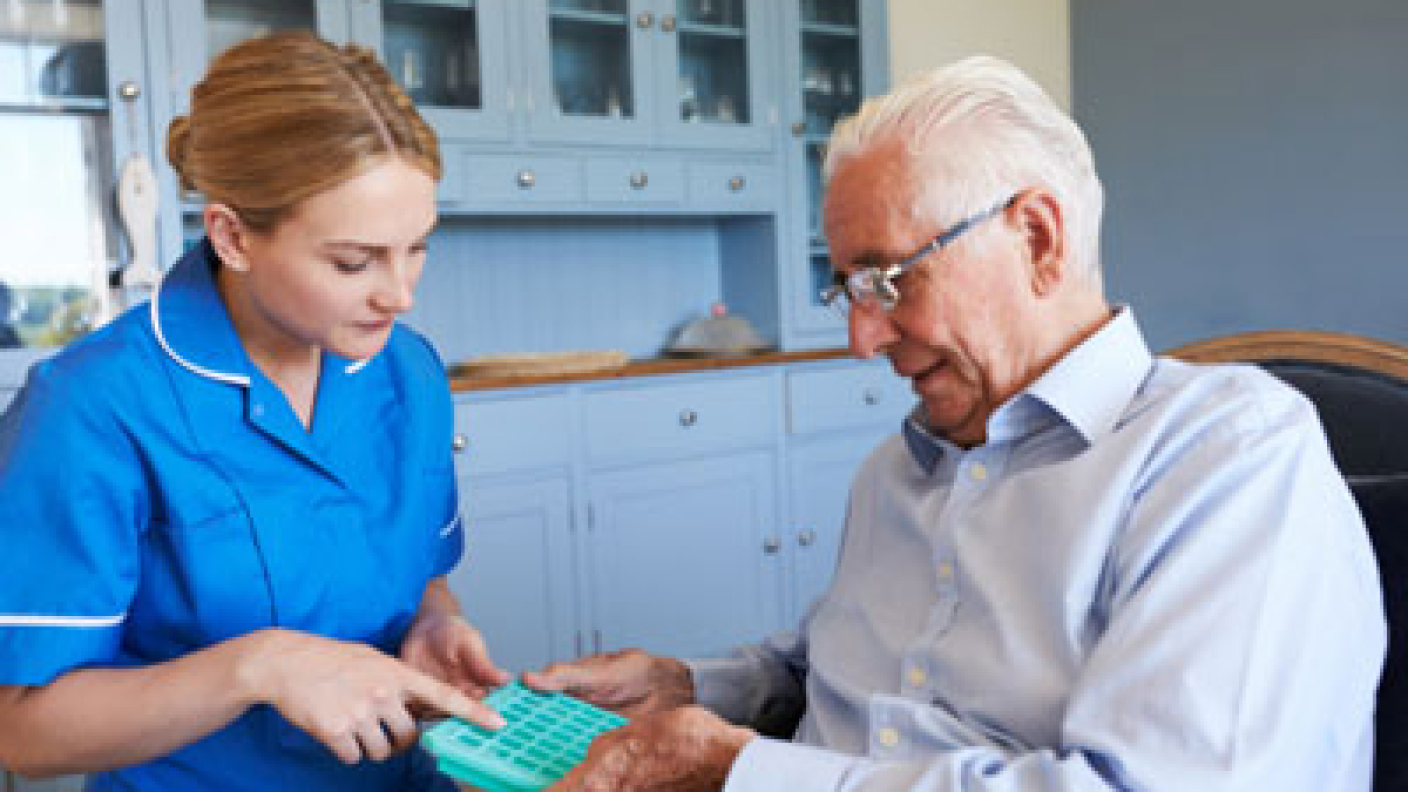 SALMON Health and Retirement staff member review a resident's medication with them while holding a pill planner