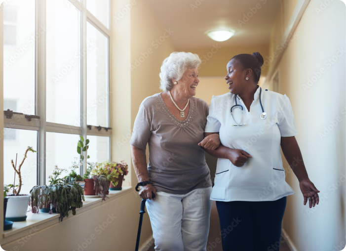 A nurse helping a senior women walking down the hall of SALMON's Beaumont Assisted Living and Rehabilitation community