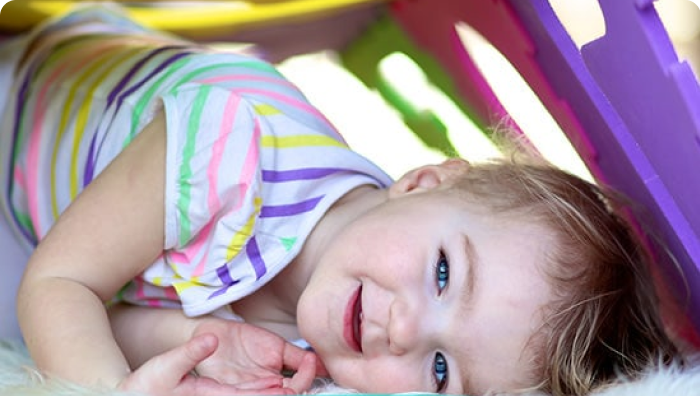Child laying down while include a plastic kids house