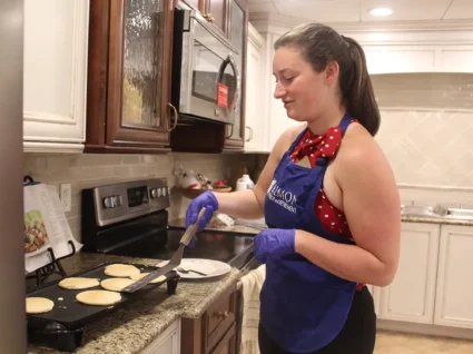 Activity Director Maggie Tompkins flipping pancakes at Whitney Place at Northborough