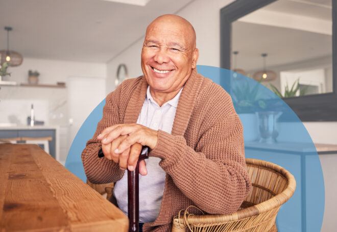Senior man with cane smiling at dining table