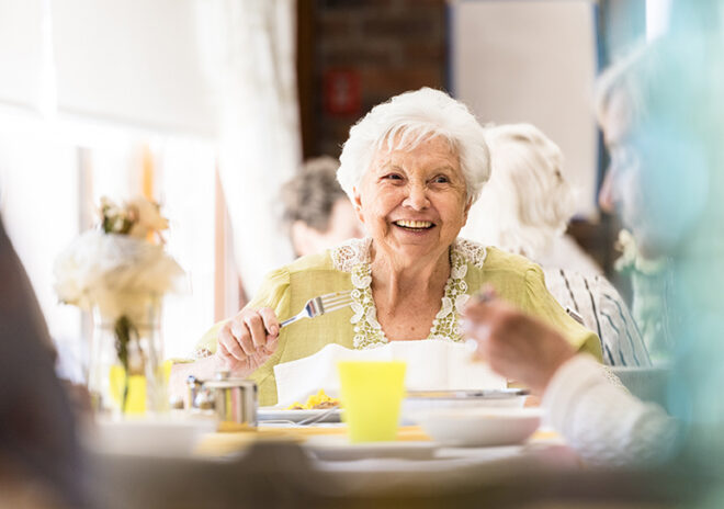 smiling senior woman eating in dining room