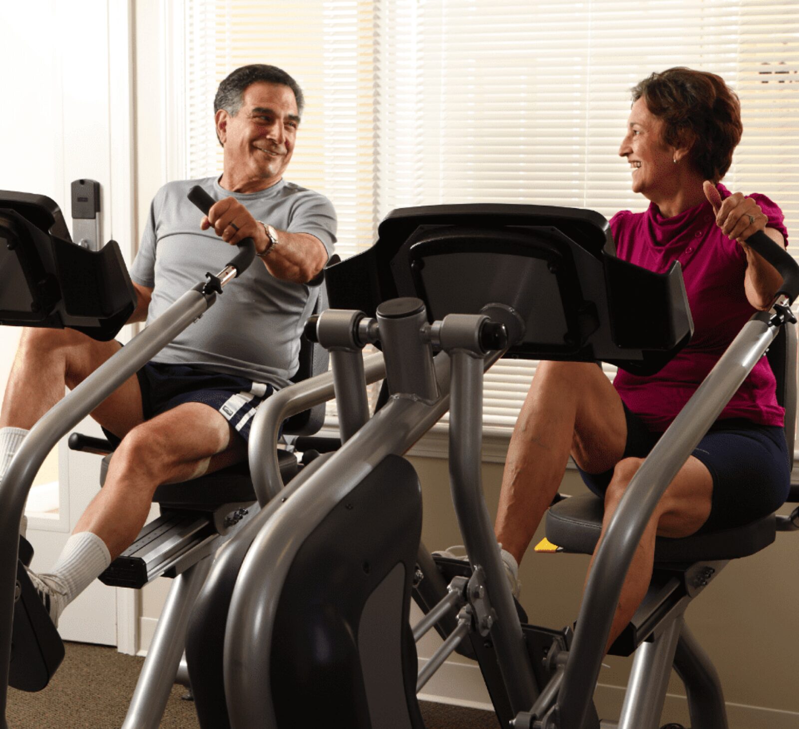 A senior man and women exercising on an elliptical machine