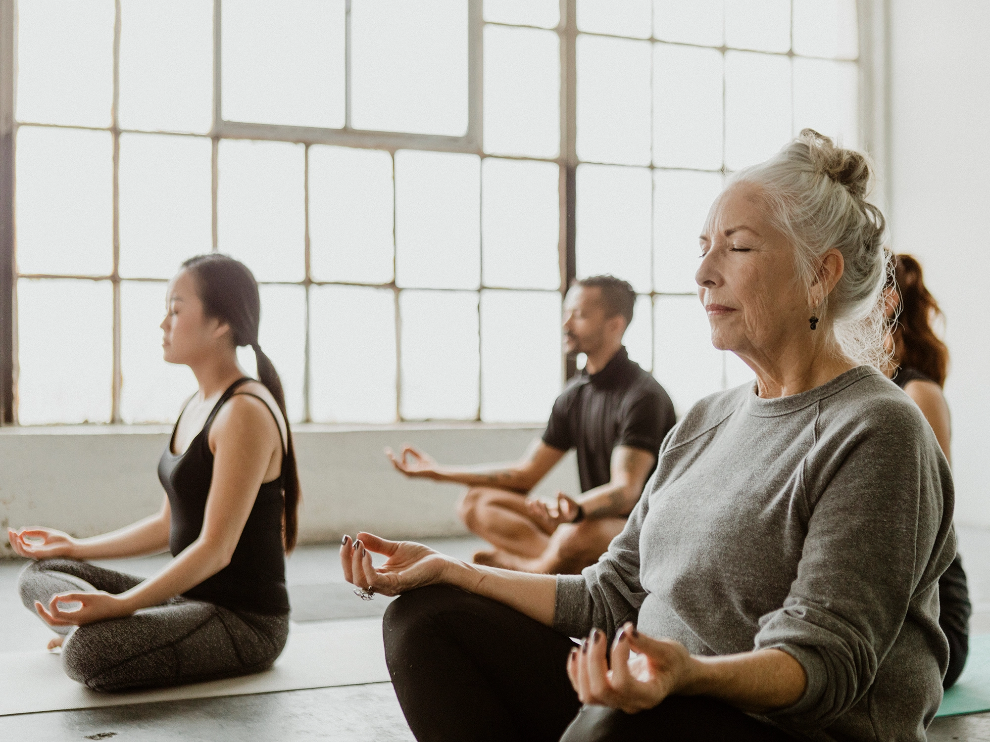 Senior woman meditating in a yoga class