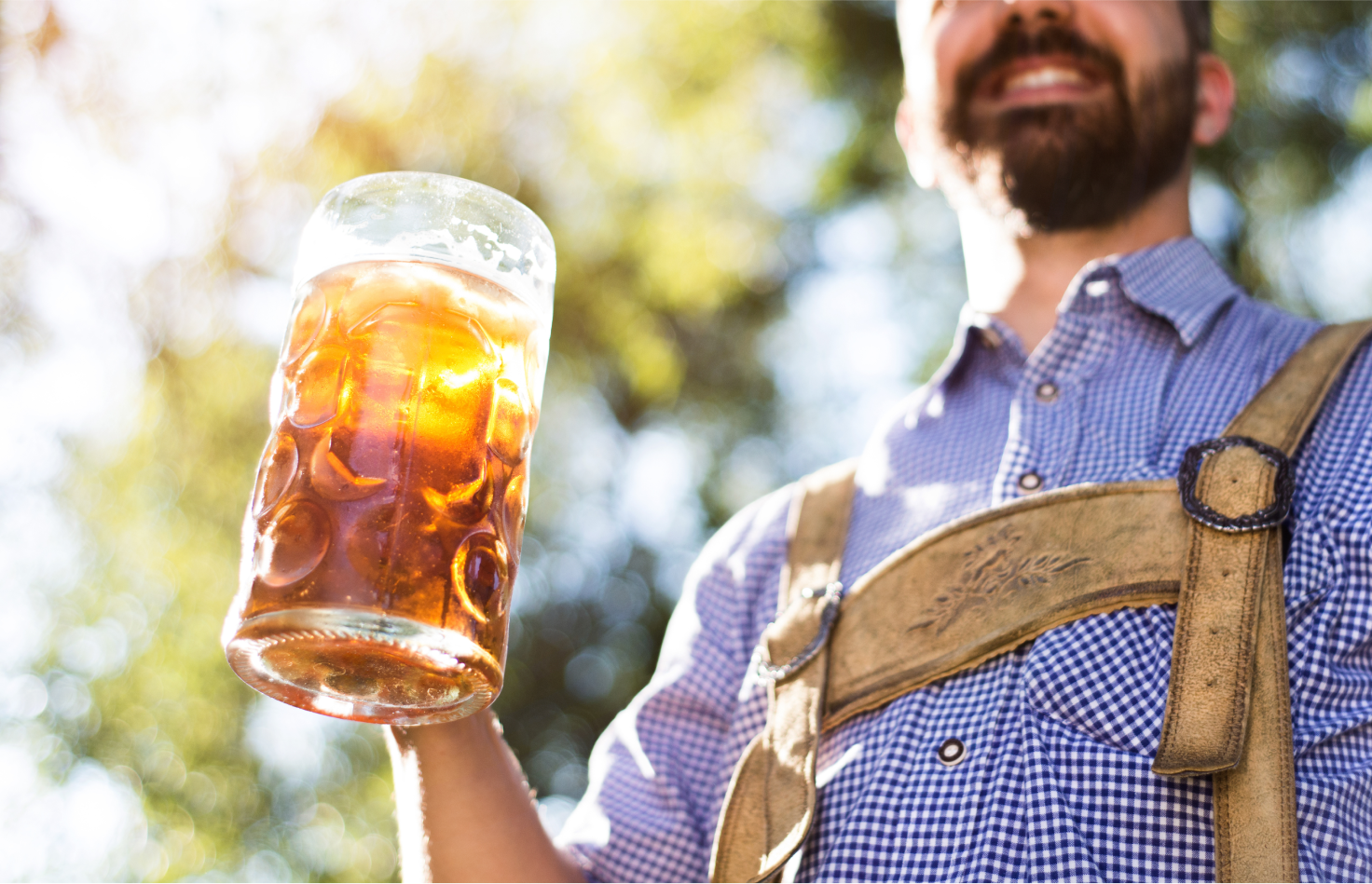 Man dressed in traditional German cloths holding a mug of beer at SALMON Health and Retirement's Oktoberfest