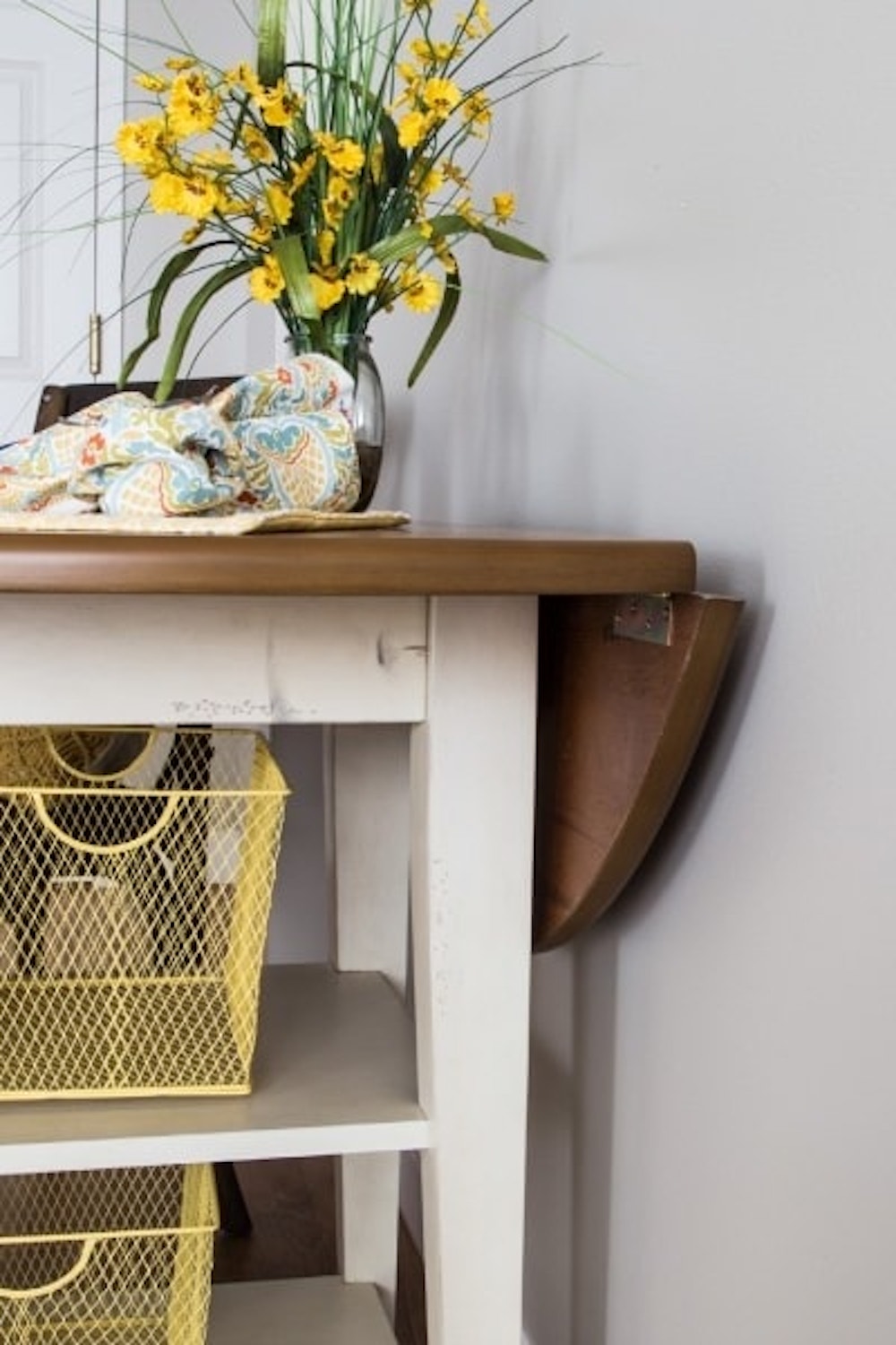 end table with a vase full of flowers siting on-top and organizing bins underneath