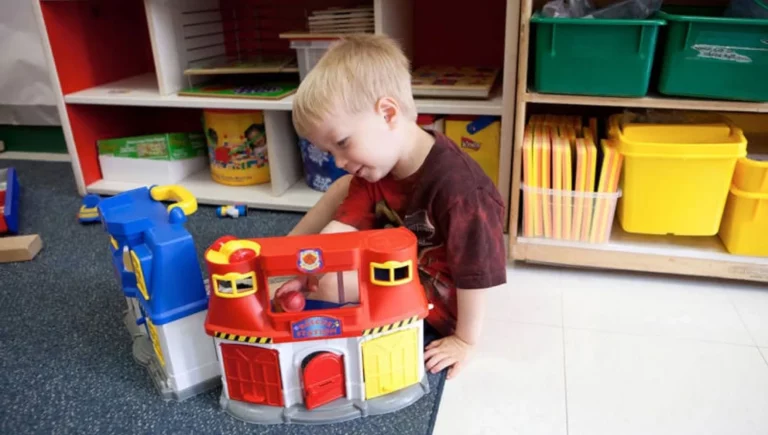 Young boy playing with a firehouse at SALMON's Early Child Education Center at Natick