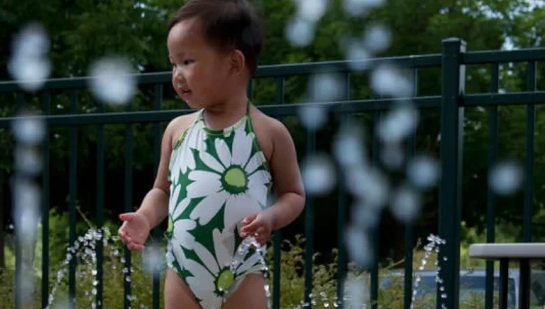 young girl wearing a bathing suit and playing with water