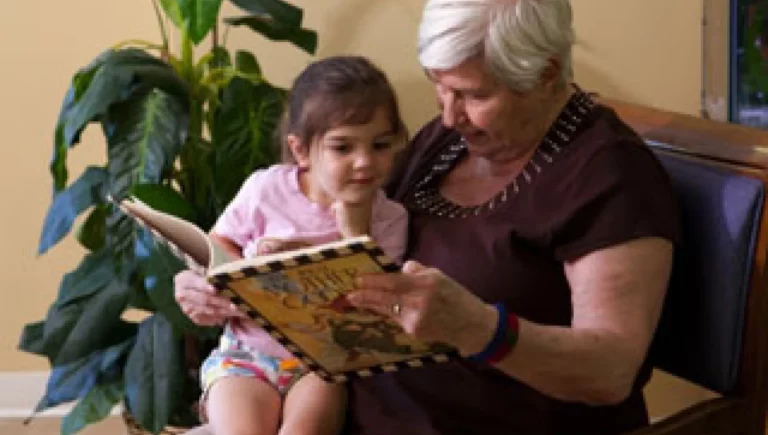 Senior woman reading a book to a little girl