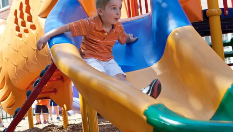 young boy sliding down a playground slide