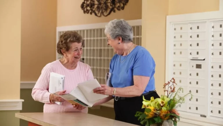 Two senior women review a magazine they got inside SALMON at Worcester The Willows's mailroom