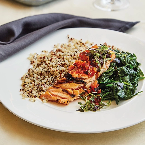 Dinner plate featuring grilled salmon, spinach, and quinoa